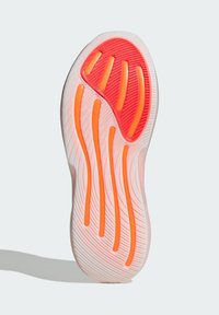 Suola di una sneaker con motivo a onde, prevalentemente bianca con accenti arancioni e grip testurizzati, progettata per trazione e supporto.