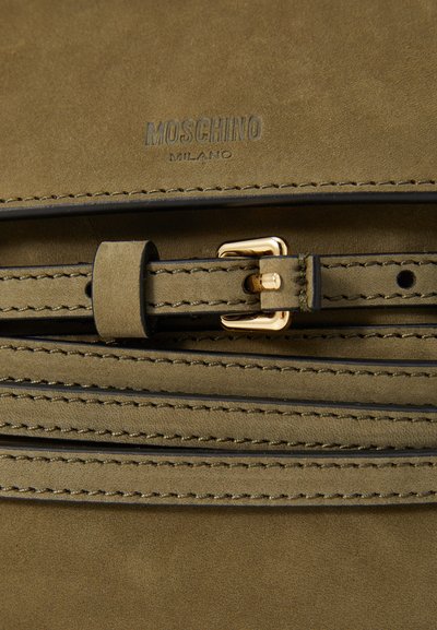 Geantă din piele sueded verde măslin cu accesorii tonificate în aur. Prezentă detalii de cusătură și o curea asemănătoare unei centuri, cu o cataramă. Logo-ul este vizibil.