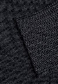 Tissu tricoté gris foncé avec une texture côtelée, présentant un poignet replié montrant une couture et une épaisseur constantes.