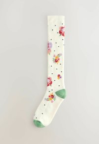 Bijela čarapa do koljena s šarenim cvjetnim uzorcima, crnim točkicama i zelenim detaljima na prstu i peti. Mekani materijal.