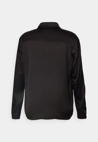 Zwarte blouse met lange mouwen, gemaakt van gladde stof, met een platte kraag en een rechte snit. Heeft zijsplitten aan de zoom.