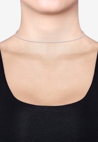 Strieborný choker náhrdelník s jemným, tenkým reťazcovým dizajnom ležiacim na kľúčnej kosti; má hladký, lesklý povrch a jednoduchý uzáver.