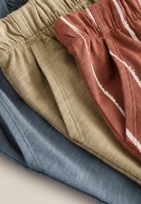 Tres pares de pantalones cortos en colores azul, beige y óxido. Los pantalones cortos tienen cinturillas elásticas y un tejido texturizado con rayas estrechas.