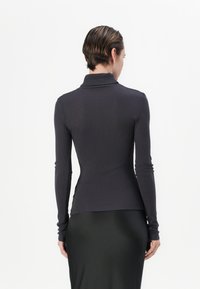 Mørkegrå rillede turtleneck med lange ærmer, tætsiddende pasform, glat tekstur, parret med en flydende sort nederdel. Enkel og tætsiddende design.