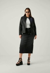 Juoda odinė striukė su užtrauktuku, balta palaidinė, juoda džinsinė midi sijonas ir masyvūs juodi kulniukai su dirželiais. Minimalistinis dizainas, elegantiškos tekstūros.