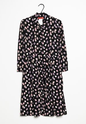 Schwarzes, langärmliges Knopfhemdkleid mit Kragen, bedeckt mit mehrfarbigen, ovalen Pünktchen, das an einem schwarzen Kleiderbügel hängt.