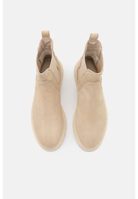 Bottines beige en daim au toucher lisse, dotées de panneaux latéraux élastiques et d'un bout arrondi, montées sur une semelle légère et texturée.
