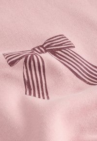 Jasnoróżowy materiał z nadrukiem ciemnoróżowej kokardy w pionowe paski. Tekstura jest miękka i gładka.