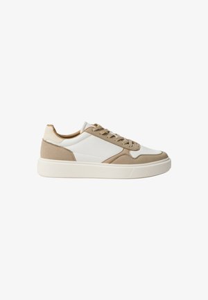 Beige-weiße Sneaker mit einem oberen Material aus strukturiertem Stoff, glatten Akzenten, runder Spitze und einer weißen Gummisohle. Ausgestattet mit einer Schnürung und einem schlanken Profil.
