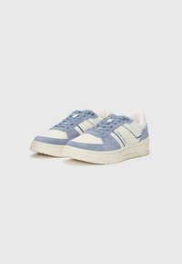 Blue and white sneakers featuring a mix of suede and smooth materials, with perforations, striped accents, and a textured sole.