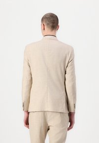 Šviesiai béžinis pritaikytas švarkas su tekstūruota medžiaga, slim fit, iškirpte ir dviem sagomis, matomas iš nugaros.