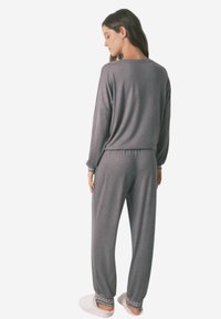 Gray loungewear set with long sleeves and elastic waist. Soft fabric, relaxed fit, and decorative accents at the cuffs of the pants.