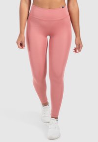 Leggings rosa a vita alta realizzati in materiale elasticizzato, con una texture liscia e un design aderente e slanciato.