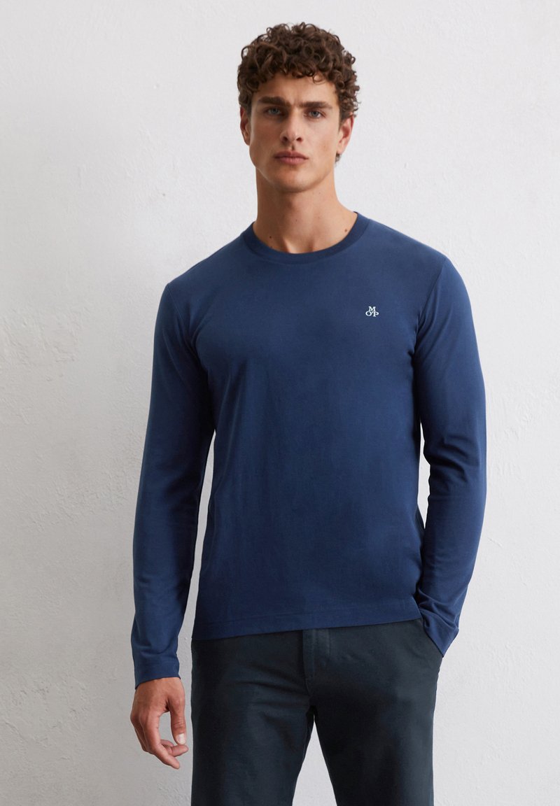T-shirt à manches longues bleu marine en coton doux ; col rond et petit logo de marque sur la poitrine ; design ajusté.