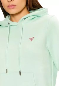 Felpa verde menta con tasca frontale, cappuccio con cordino e piccolo logo a triangolo rosso sul lato sinistro del petto. Tessuto morbido e con texture.