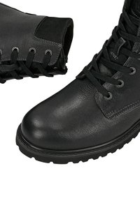 Scarpe da trekking in pelle nera con un design elegante, punta rotonda, superficie testurizzata e suole in gomma durevoli, dotate di lacci e dettagli metallici.