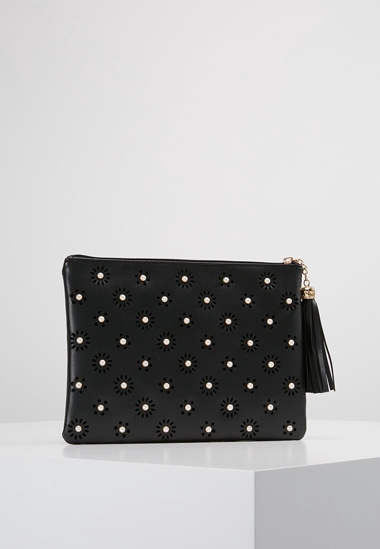 Pochette en cuir noir avec fermeture éclair dorée, décorée de motifs floraux perforés et de petites embellissements perle, avec une fermeture à pompon.