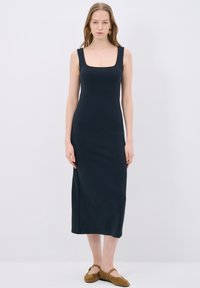 Navy blue jumpsuitt ilman hihoja, neliökaula-aukolla, vartalonmyötäisellä siluetilla ja polvipituisella leikkauksella. Suloinen rakenne ilman näkyviä kuvioita.