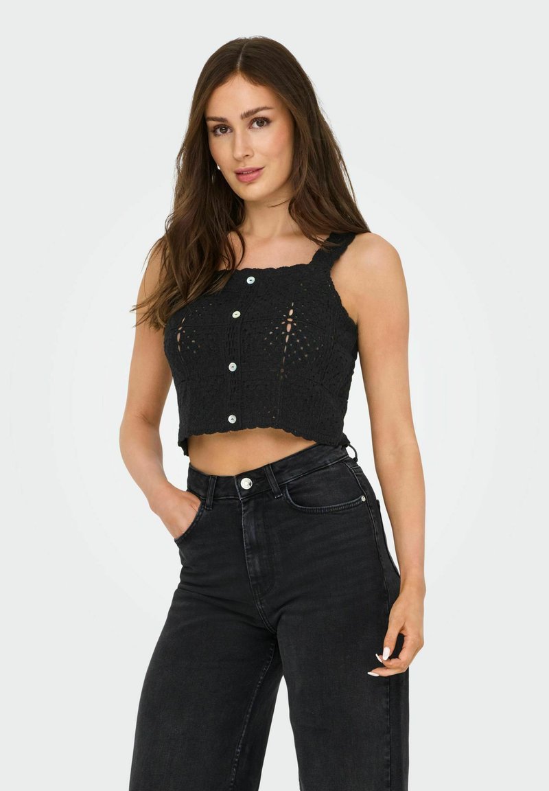 Top court en crochet noir avec un ourlet en dents de scie, des bretelles ajustables et des boutons sur le devant, associé à un jean noir taille haute.