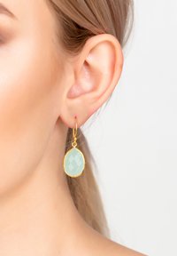 Gold teardrop earrings with a faceted mint green stone, showcasing a polished texture and a simple hook design.
