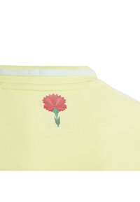 Yellow short-sleeve shirt with a round neckline. Features a red flower graphic on the back and a light blue trim on the collar.