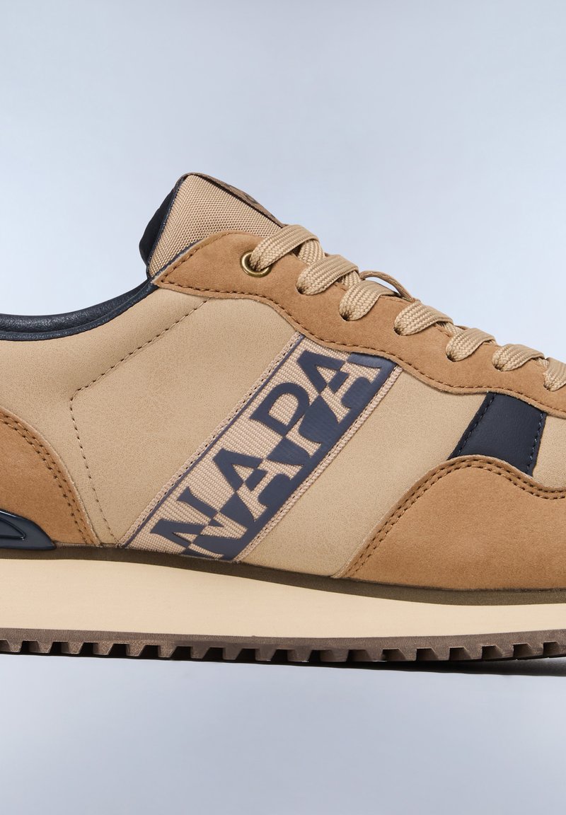 Zapatillas beige y marrón con una franja azul marino que presenta la palabra "NAPA", fabricadas en ante y cuero suave, con una suela texturizada.