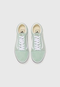 Zapatillas de ante verde con cordones blancos, franjas laterales y suela de goma negra. Punta redondeada y superficie superior texturizada.