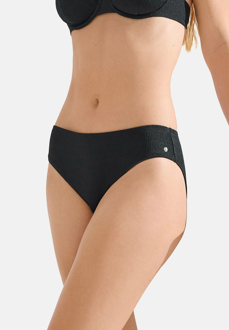 Bas de bikini noir avec une taille haute, en tissu texturé, et un petit accent métallique sur le côté. Design simpliste et moderne.