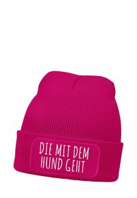 Fuchsia beanie hat with a ribbed texture and a folded cuff, featuring white text on a rectangular patch that reads "DIE MIT DEM HUND GEHT."