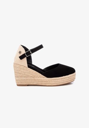 Zapato de cuña de ante negro con correa en el tobillo, que presenta un tacón de yute trenzado y un panel trasero texturizado de color beige con patrón.