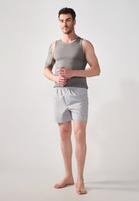 Grå tanktop med tætsiddende design og ribbet tekstur, parret med letvægts stribede shorts med elastisk talje.