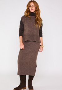 Ensemble en tricot brun composé de deux pièces, comprenant un haut sans manches à col montant et une jupe longue; les deux présentent des bords côtelés et une texture douce.