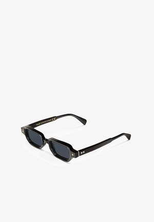 Gafas de sol rectangulares negras con lentes oscuros, con un acabado brillante, montura angular y detalles dorados en las patillas.