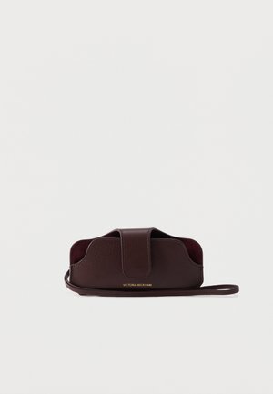 Pochette bracelet en cuir marron avec fermeture à rabat et logo doré Victoria Beckham centré sur le devant.
