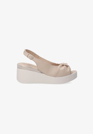 Beige leather slingback wedge sandal with a rounded open toe, pleated detail, shiny silver accent on the heel, and a white platform sole.