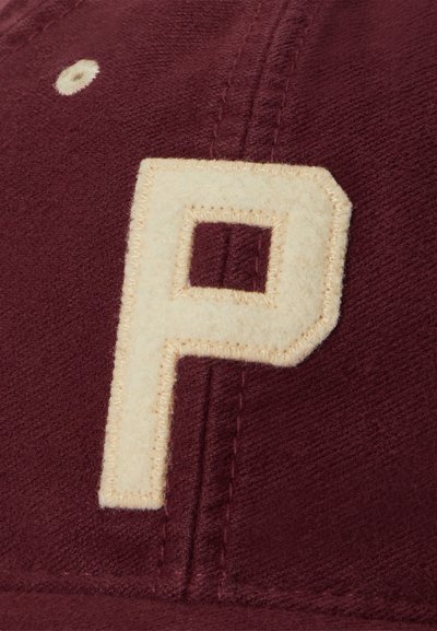 Bordový látkový čiapka s prišitým krémovým znakom "P" a krémovým prešitým ventilačným otvorom na ľavej hornej strane.
