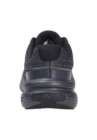 Zapatilla deportiva negra con parte superior de tela texturizada, talón redondeado y suela de goma con un prominente logo de Nike y surcos.