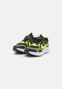 Baskets de sport noires et jaune fluo avec tige en mesh, col rembourré et sangles Velcro ; semelle en caoutchouc blanche chunky et semelle texturée.
