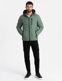 Grön vadderad jacka med huva, dragkedja fram och bröstficka, tillsammans med svarta cargo-byxor och svarta sneakers.