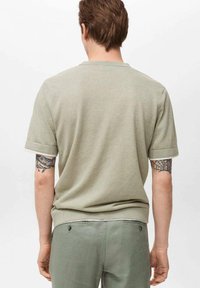 Tricou scurt cu maneci scurte, de culoare verde deschis, cu decolteu rotund. Material din bumbac moale. Prezintă maneci rulate și o textură netedă, fără decorațiuni.