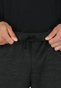 Zwarte, gestructureerde joggers met een elastische tailleband voorzien van een trekkoord. De stof is zacht en duurzaam, ontworpen voor comfort.