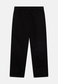 Černé tepláky s elastickým pasem, střihem s rovnými nohavicemi, hladkou texturou a jemným logem na levé straně.