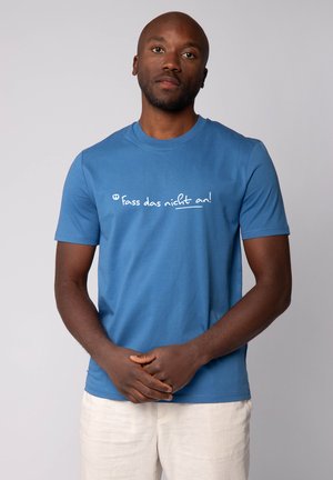 Blau katoenen T-shirt met korte mouwen, met op de borst de witte tekst "fass das nicht an!" gedrukt, gladde textuur.