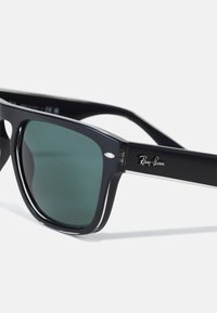 Ochelari de soare negri Ray-Ban cu lentile verzi. Design cu ramă pătrată, finisaj lucios și accente argintii pe laturi. Logo gravat pe braț.