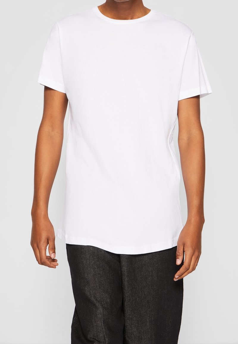 T-shirt en coton blanc à manches courtes, avec un col rond et une coupe décontractée. Ne présente aucun motif ou accent visible.