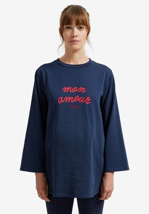 Navy long-sleeve shirt with a round neckline featuring red text "mon amour" and "Charlie" below it. Soft fabric, relaxed fit, minimal design.
