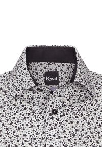 Camicia a maniche corte bianca con un motivo floreale nero. Presenta un colletto classico, chiusura con bottoni e una texture morbida. Etichetta del brand visibile.