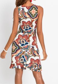 Šaty bez rukávů s květinovým vzorem v červené, modré, zelené a krémové barvě. Mají volánový lem a přiléhavý střih. Vyrobené z lehké látky.