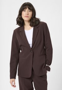 Bruine getailleerde blazer, met reverskraag, sluiting met één knoop, twee voorzakken, gecombineerd met een witte top, gladde stof, elegante snit.