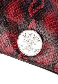 Portafoglio con texture in pelle di serpente rossa e nera, caratterizzato da un accento circolare argento con la scritta "JOOP! JEANS" inciso in una bandiera decorativa.